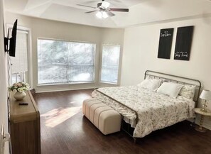 Une chambre à coucher comprenant un lit, un banc, un ventilateur de plafond et deux éléments de décoration fixés au mur.