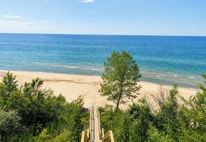 A beach with a wooden walkway leading to the shore, surrounded by greenery. - Lake Michigan Retreat | Private Beach & Lawn (Coloma)