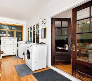 A laundry room with a washing machine, dryer, and a wooden door leading to a living area. - Lake Michigan Retreat | Private Beach & Lawn (Coloma)