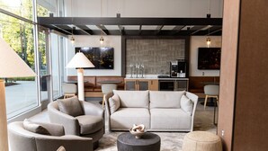 En moderne stue med sofa, lænestole, sofabord og lampe.
