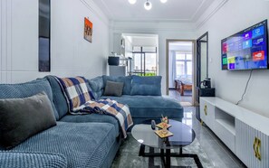 A modern living room with a sectional sofa, a coffee table, and a flat-screen TV mounted on the wall. - Sleek Kilimani 1BR Apartment (Nairobi)