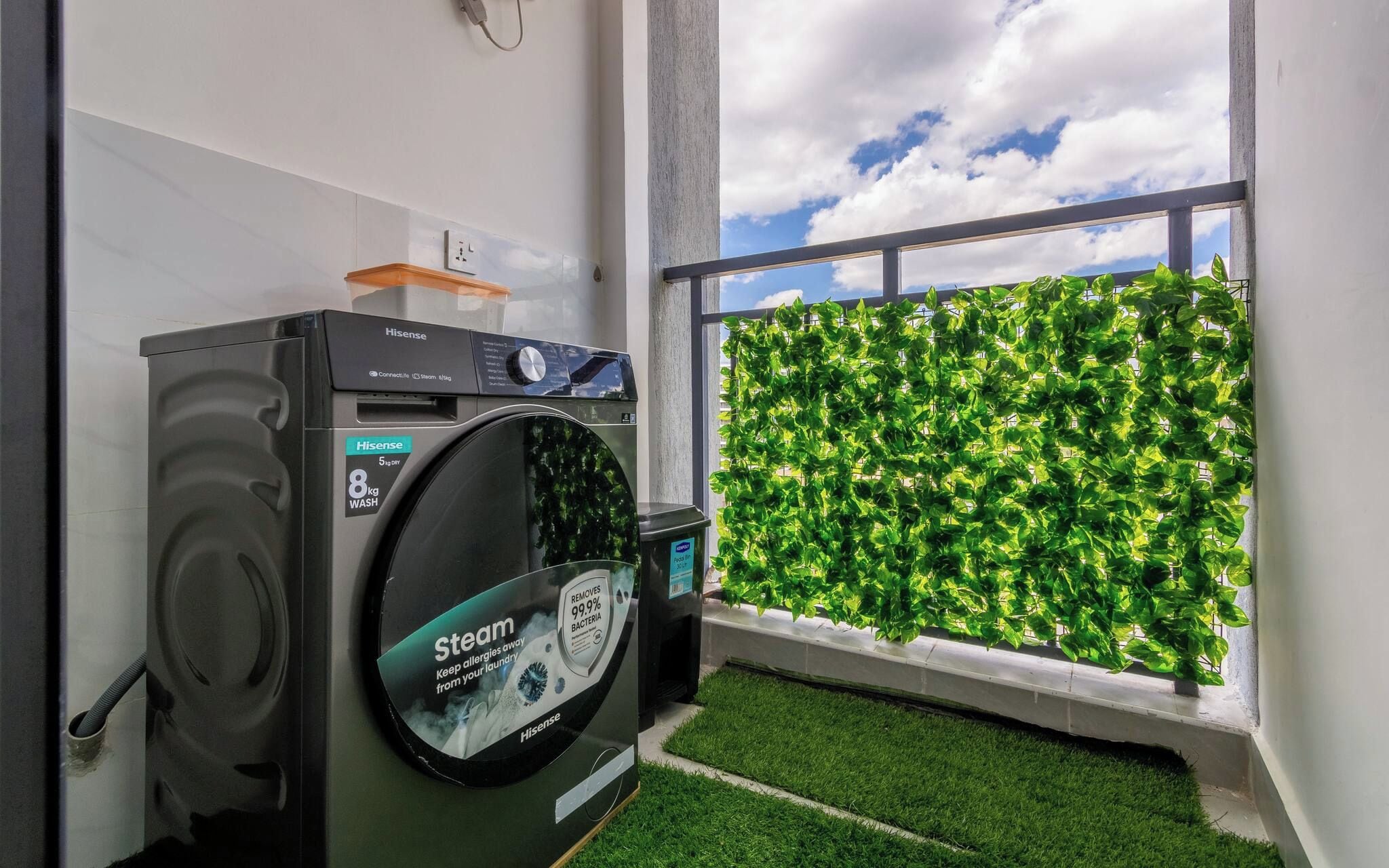 A Hisense washing machine in a room with a view of a green wall and a window.