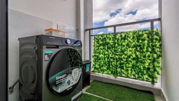 A Hisense washing machine in a room with a view of a green wall and a window.