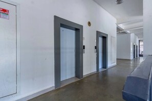A long, empty hallway with doors and an elevator. - Sleek Kilimani 1BR Apartment (Nairobi)