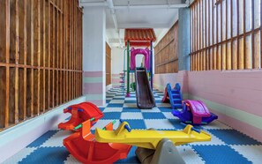 A children's play area with a slide, climbing structures, and a colorful floor. - Sleek Kilimani 1BR Apartment (Nairobi)