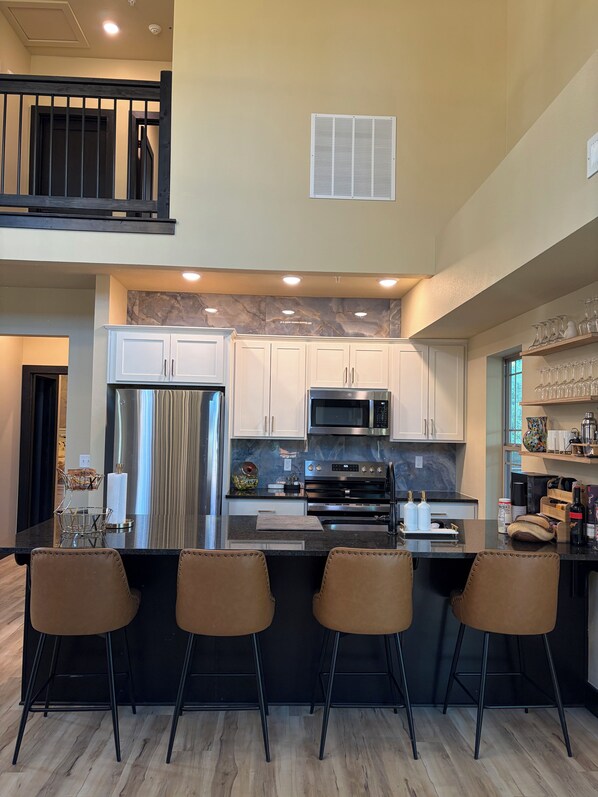 A modern kitchen with a central island, bar stools, and stainless steel appliances.