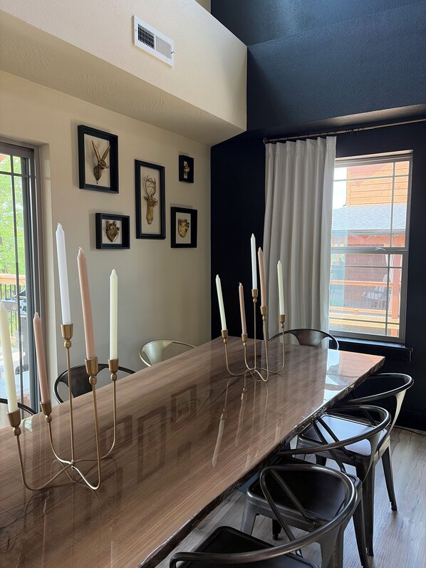 A dining area with a long wooden table, six candles, and framed animal heads on the wall.
