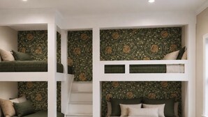 Una habitación con literas, la litera inferior con cubrecama verde y una escalera que lleva a la litera superior.