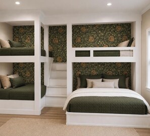 Una stanza con un letto a castello, l'ultimo letto con una coperta verde e una scala che conduce al letto superiore.