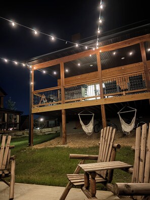 Un terrazzo in legno con luci a catena, un'amaca e una sedia.