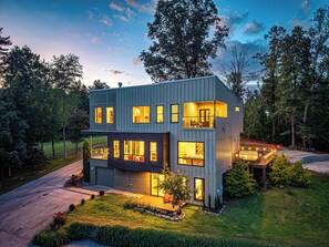 Une maison moderne à deux étages, dotée de nombreuses fenêtres, d’une pelouse bien entretenue et d’une allée.