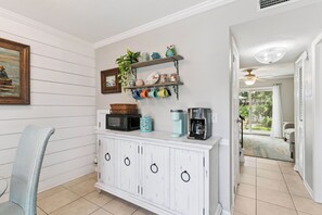 A kitchen with white cabinetry, a microwave, a coffee maker, and a shelf with decorative items. - Shore Thing- 2 Bed, 2.5 Bath Condo (St. Simons Island)
