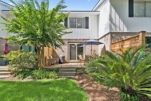 A residential backyard with a patio, outdoor furniture, a covered seating area, and a variety of plants. - Shore Thing- 2 Bed, 2.5 Bath Condo (St. Simons Island)