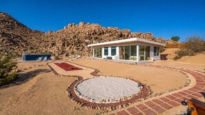 A modern building with a circular patio, surrounded by a landscaped area with a rock border.
