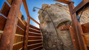 A wooden staircase leading to a rock formation with a showerhead.