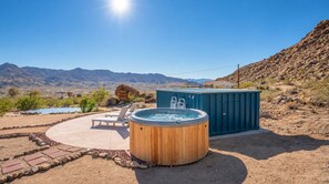A hot tub and a pool in a desert landscape with mountains in the background.