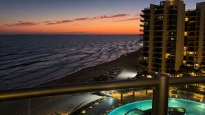 Een hotel met zwembad, uitzicht op het strand en een zonsondergang.