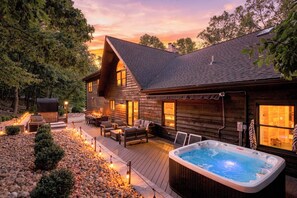 A wooden cabin with a hot tub, outdoor seating, and a deck.