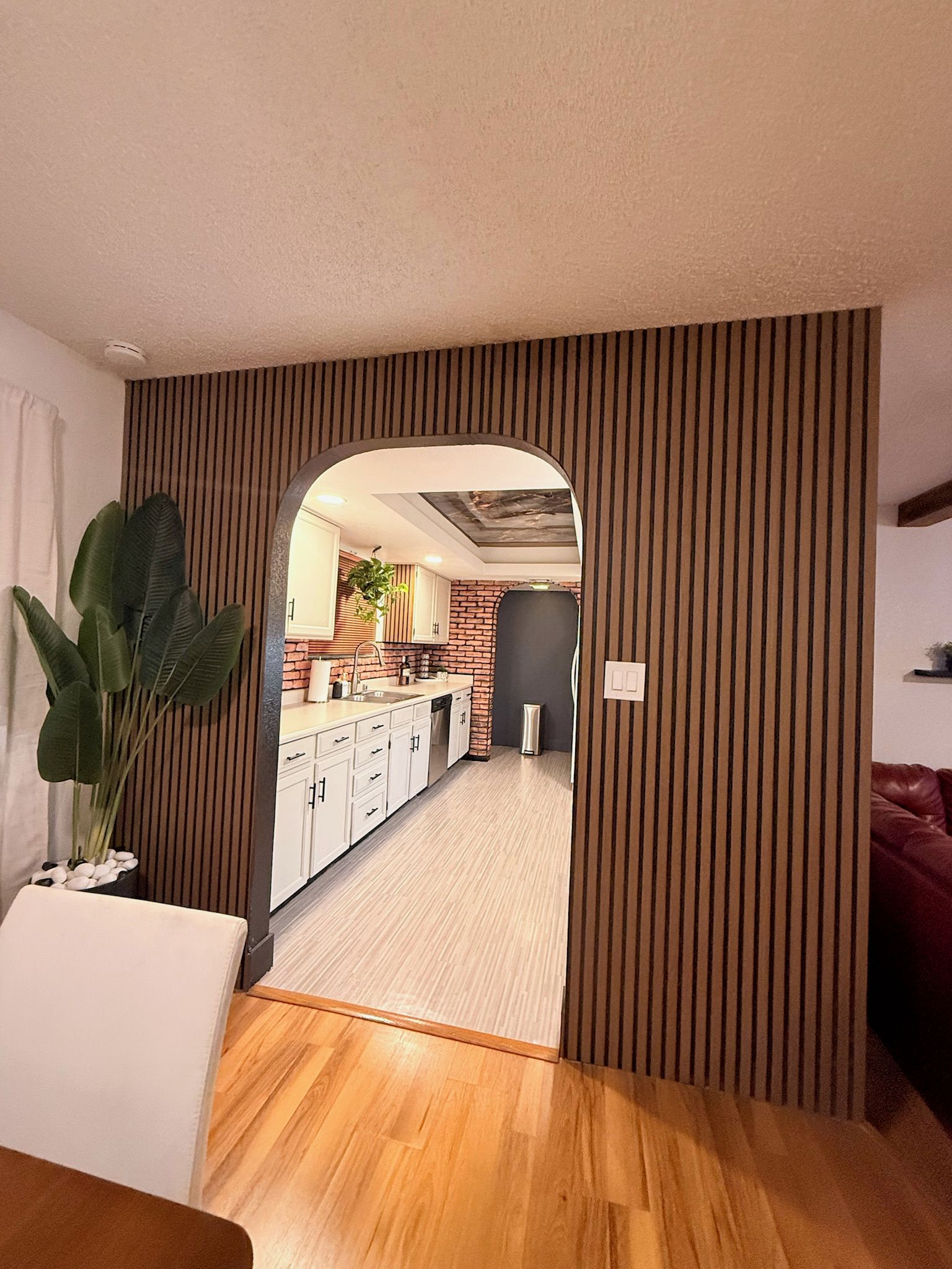 Eine moderne Küche mit weißen Schränken, Holzboden und Backsteinwand.