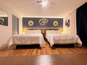 Ein Hotelzimmer mit zwei Betten, einem Deckenventilator und Wanddekorationen.