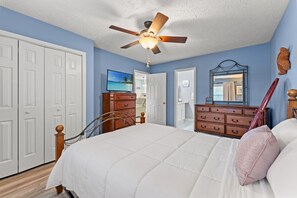 Ein Schlafzimmer mit Bett, Schminktisch und Deckenventilator.