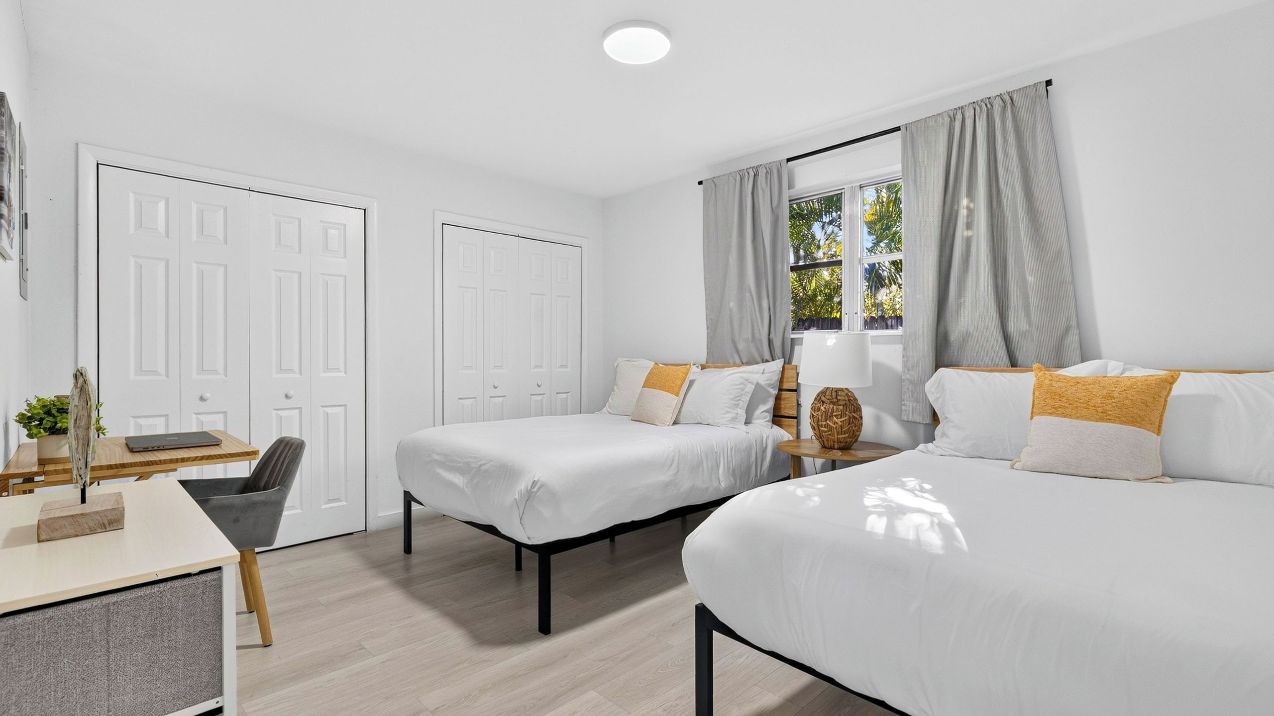 A hotel room with two beds, a desk, and a chair.