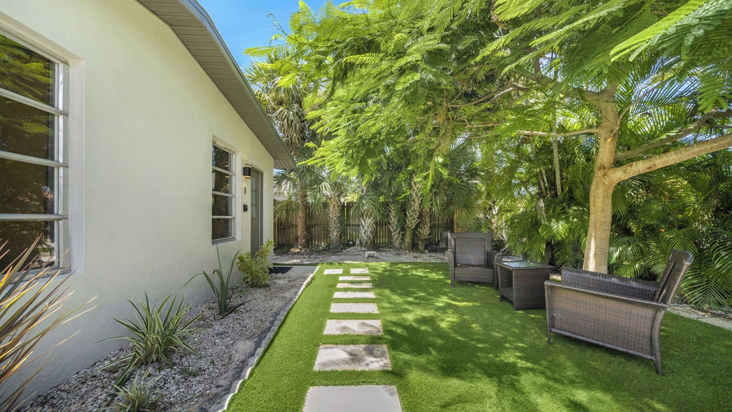 A modern house with a paved patio, outdoor furniture, and lush greenery.