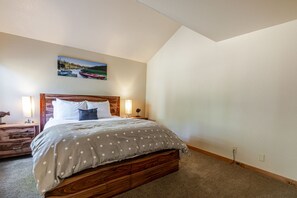Una camera da letto con un letto di legno, due lampade sui comodini, un comodino e un quadro appeso al muro.