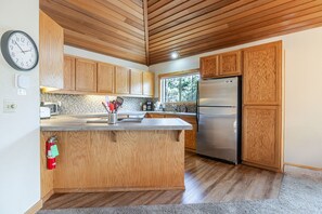 A modern kitchen with wooden cabinets, a stainless steel refrigerator, and a built-in island. - 2 Sandhill - Family-Friendly Sunriver Retreat Near Fort Rock Park with 8 SHARC Passes (Sunriver)