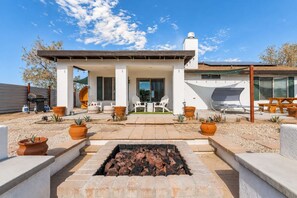 A modern house with a patio area, outdoor seating, and a fire pit. - Sun Mesa Sanctuary · Pickleball, Pool, Sauna (Joshua Tree)