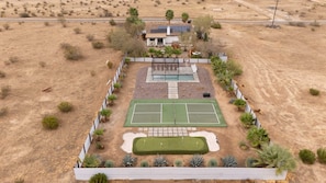 A residential property with a tennis court, a swimming pool, and a fenced garden area. - Sun Mesa Sanctuary · Pickleball, Pool, Sauna (Joshua Tree)