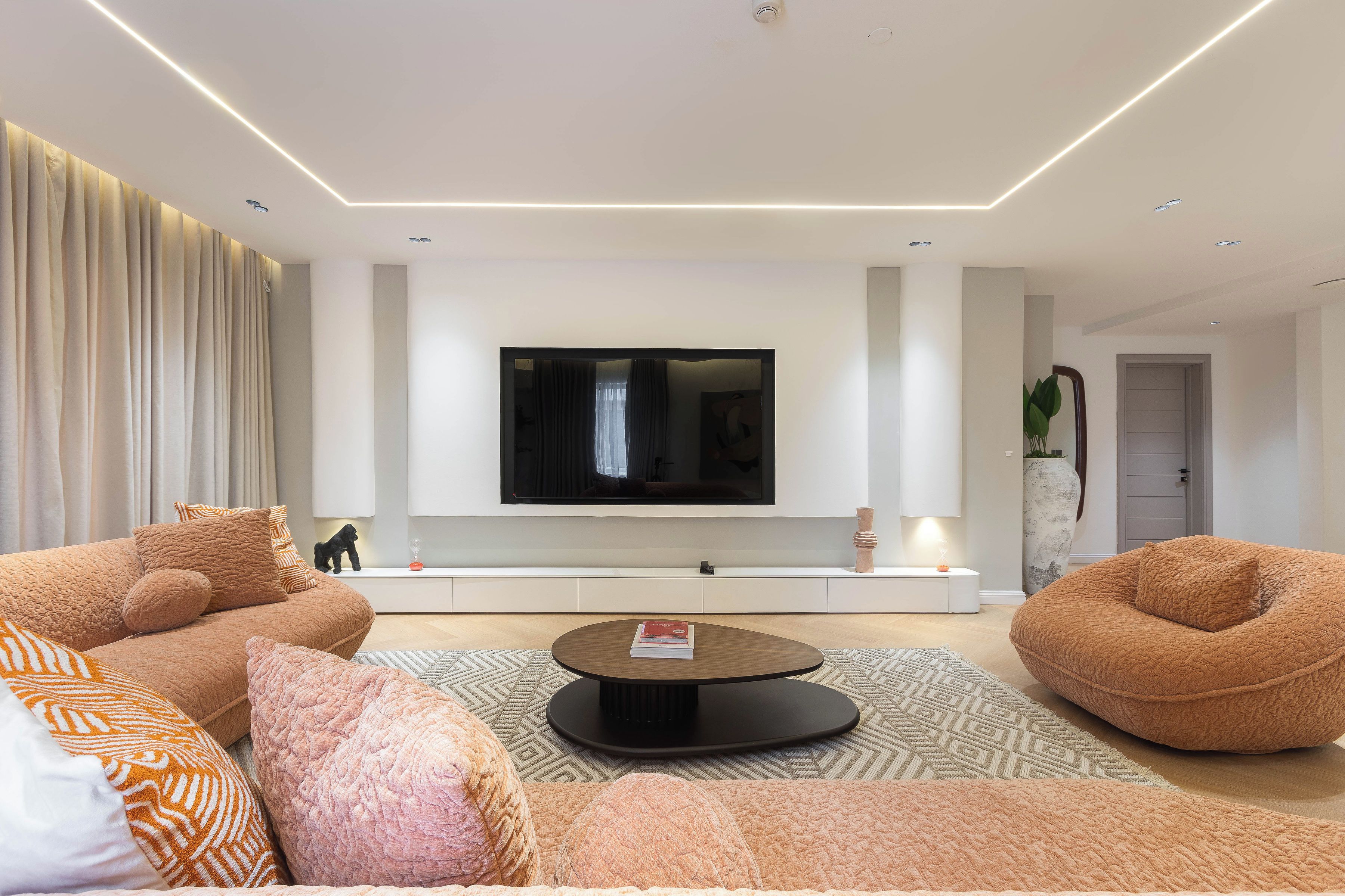 A modern living room with a flat-screen TV mounted on the wall, a sofa, a coffee table, and a patterned rug.