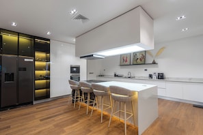 A modern kitchen with a central island, bar stools, and a built-in oven.