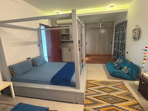 A modern bedroom with a bed, a sofa, and a patterned rug. - Optimus stay'z (Tirupporur)