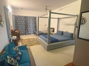 A bedroom with a four-poster bed, a sofa, a desk, and a patterned curtain. - Optimus stay'z (Tirupporur)