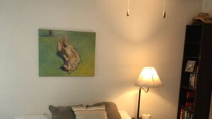 Ein Schlafzimmer mit Bett, Deckenventilator, Gemälde, Lampe und Bücherregal.