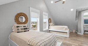 A bedroom with two beds, a ceiling fan, and a view of the outside.