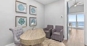 A room with a round wooden table, two grey armchairs, and four framed floral artworks on the wall. - Ocean-View Home | 7BR Retreat (Panama City)