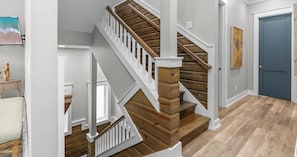 A staircase with wooden steps and white railings, leading to an upper floor.
