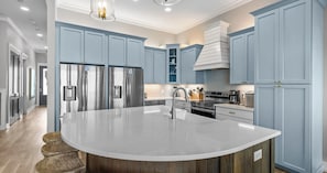 Una cocina moderna con una isla grande, electrodomésticos de acero inoxidable y armarios azul claro.