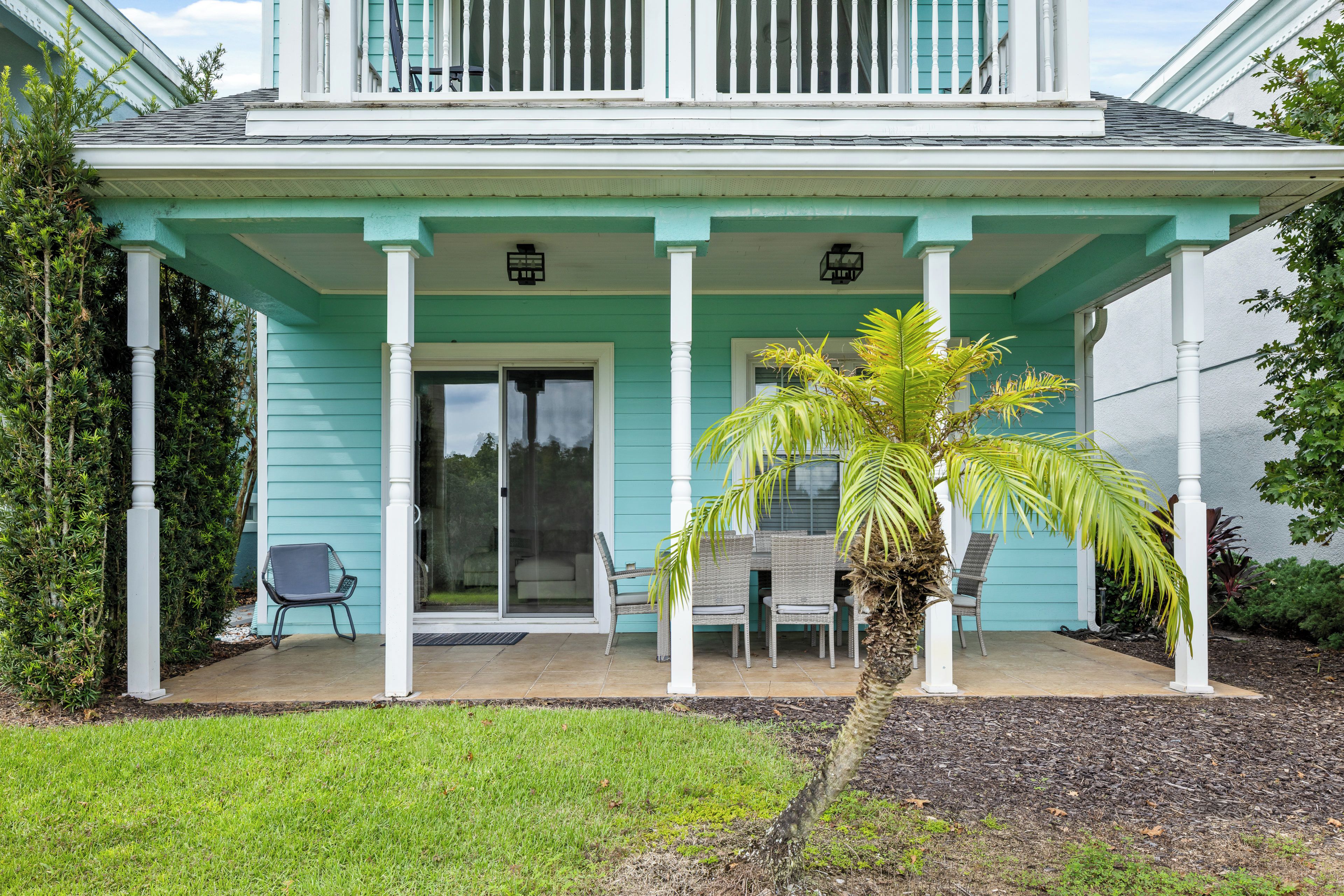 A house with a covered porch, a sliding glass door, and a small outdoor seating area with chairs.