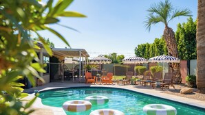 Ein Swimmingpool mit Luftmatratzen, Liegestühlen und Sonnenschirmen.
