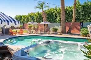 A swimming pool with hot tubs, lounge chairs, and umbrellas.