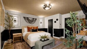 Ein modernes Schlafzimmer mit einem großen Bett, Nachttischen, einer Stehlampe, einem Wandbild und einem Blumentopf.