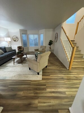 Ein geräumiges Wohnzimmer mit Holzboden, einer Treppe und Blick ins Freie.