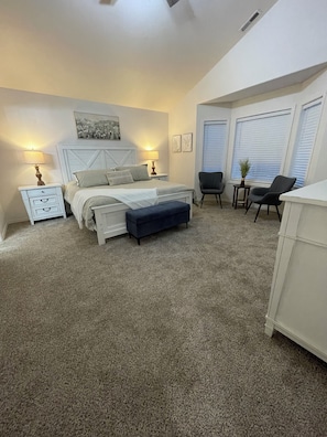 A bedroom with a bed, bedside tables, a chair, and a small table with a plant. - Comfort Pasco Townhome • 3BR • Near Ball Fields (Pasco)
