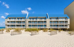 A beachfront hotel with multiple balconies, a sandy beach in front, and a clear blue sky. - 3BR Gulf Front condo with Amazing Views - sleeps 10 - Pet Friendly (Gulf Shores)