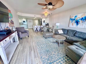 A modern living room with a sofa, armchair, coffee table, and a dining area with chairs and a table. - 3BR Gulf Front condo with Amazing Views - sleeps 10 - Pet Friendly (Gulf Shores)