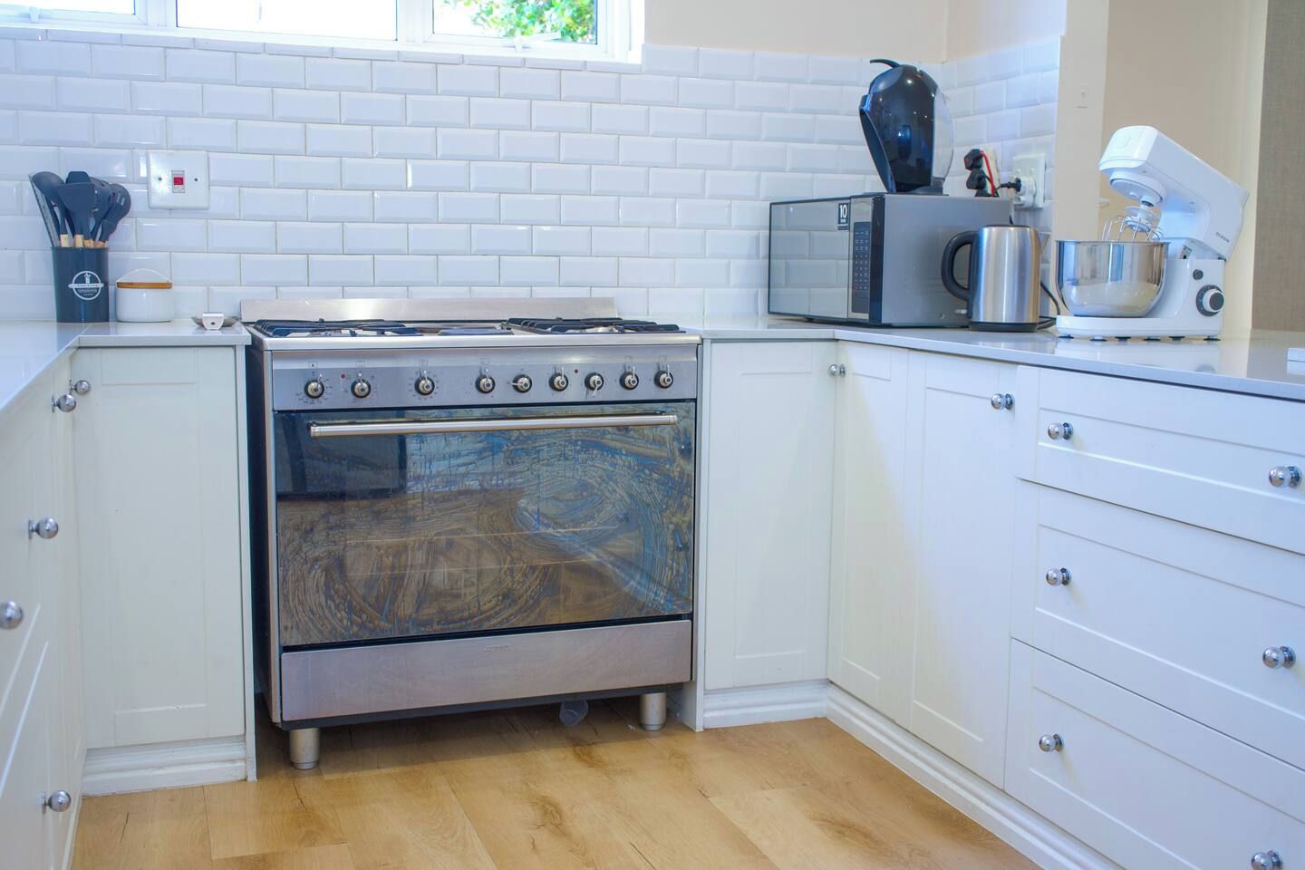 Een keuken met een roestvrijstalen kookplaat, witte kastjes en een magnetron.