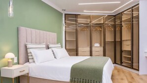 Quarto com cama, mesa de cabeceira e closet espaçoso com espaço para pendurar roupas.